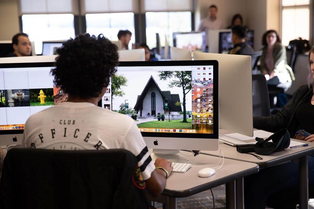 A student sits in the art & design lab working on a photograph of Norton Chapel