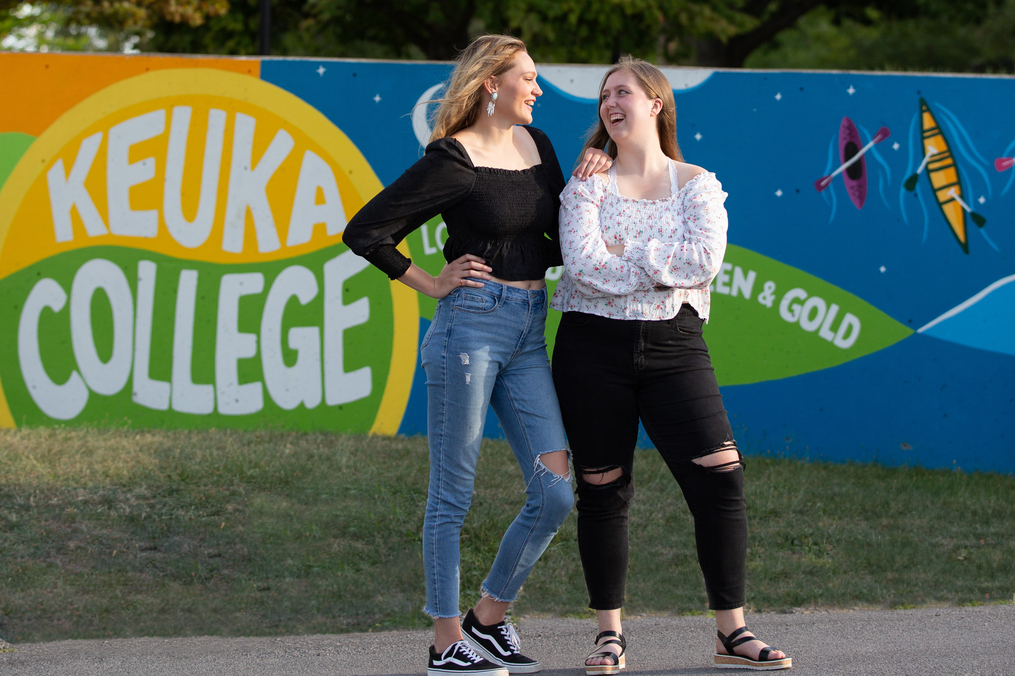 Sarah Tower '22 and Sydnie Brown '22 posing in front of the mural they designed and painted by Lightner Library