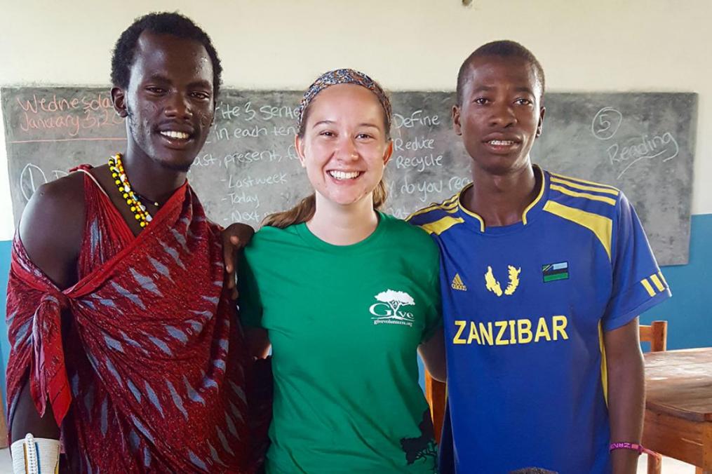 Tessa Alianell posing with two young men in a classroom on her trip